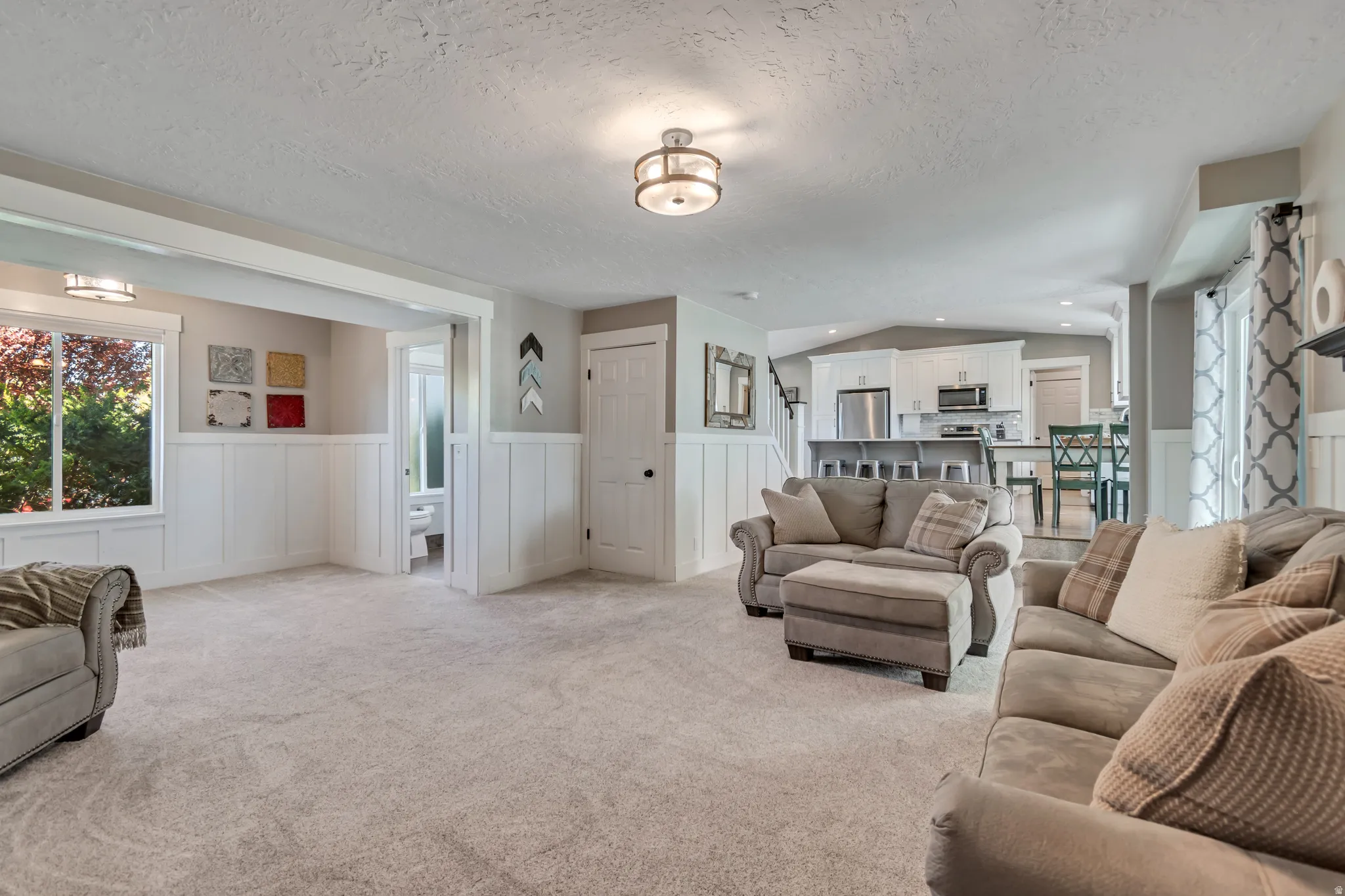 Living area featuring a wainscoted wall, a decorative wall, plenty of natural light, and light carpet