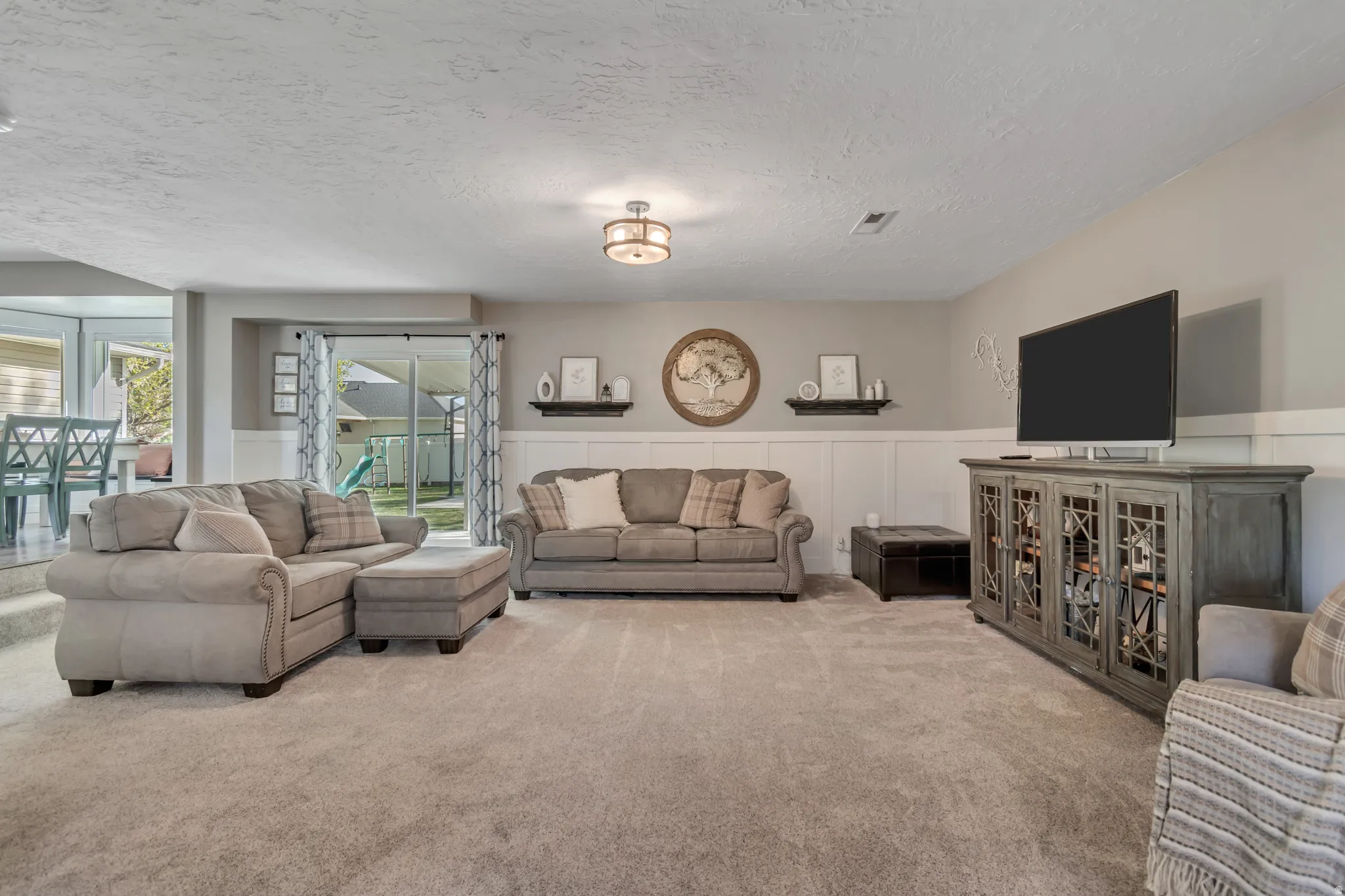 Carpeted living area with a textured ceiling and wainscoting