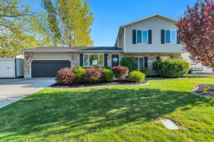 Split level home featuring brick siding, a garage, concrete driveway, and a front yard