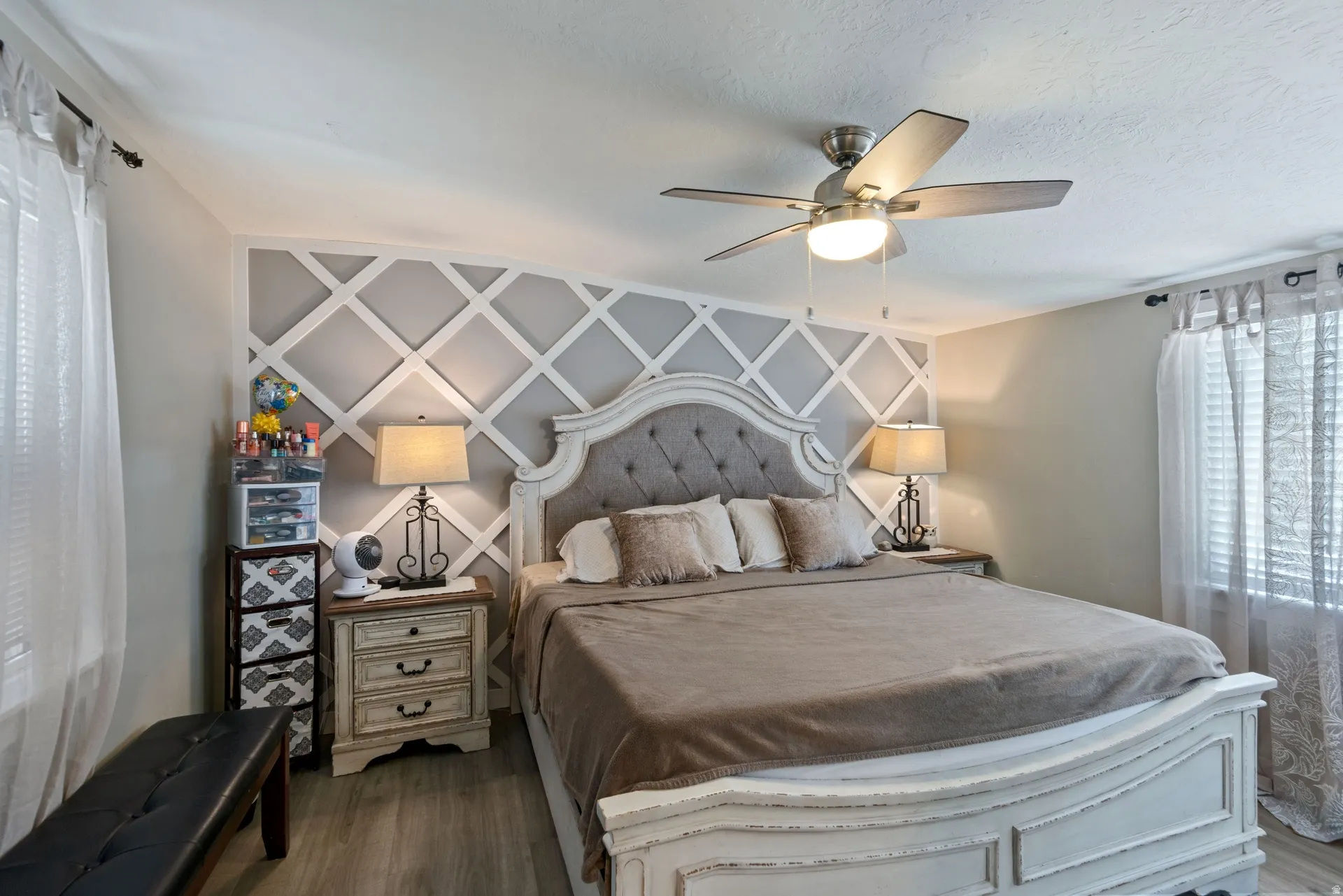 Bedroom featuring ceiling fan, dark wood-style flooring, and an accent wall