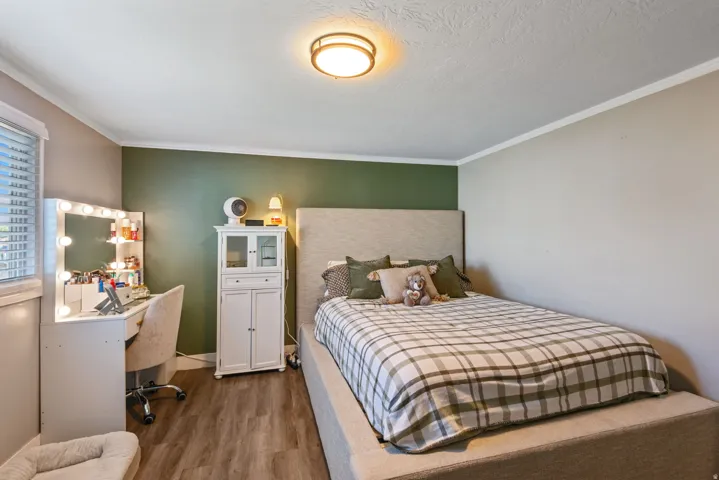 Bedroom featuring dark wood-style floors and crown molding
