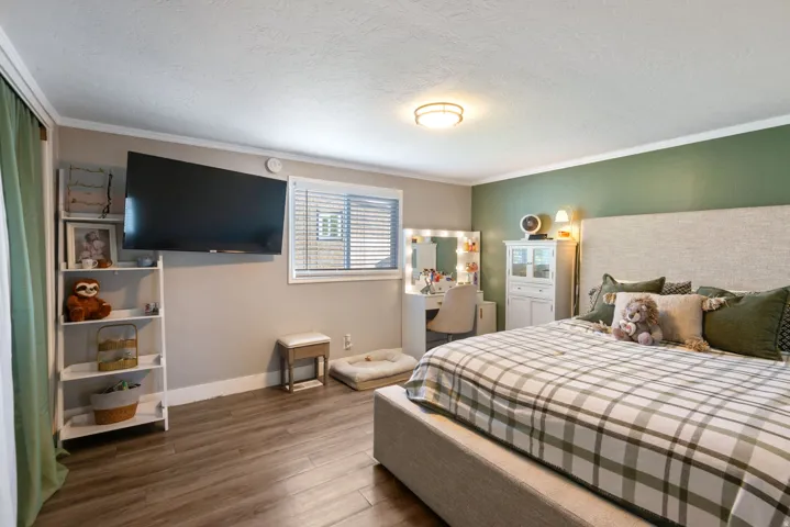 Bedroom with dark wood finished floors, a textured ceiling, and crown molding