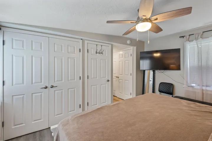 Bedroom with a closet, ceiling fan, and light wood-style flooring