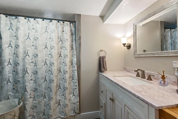 Full bath with vanity, a textured ceiling, and a shower with curtain