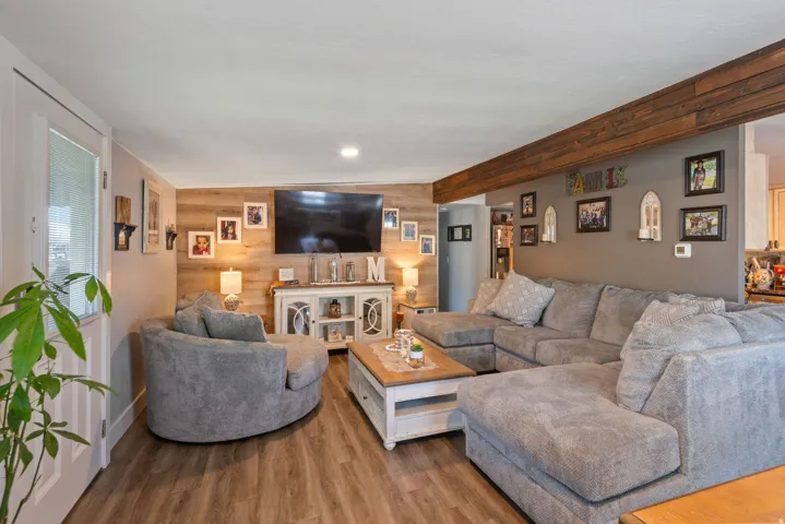 Living room featuring wooden walls, an accent wall, and wood finished floors