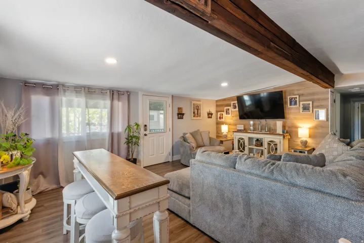 Living area featuring wood walls, beamed ceiling, wood finished floors, and an accent wall