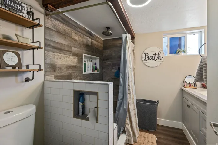 Bathroom with vanity, tiled shower, dark wood finished floors, and a textured ceiling