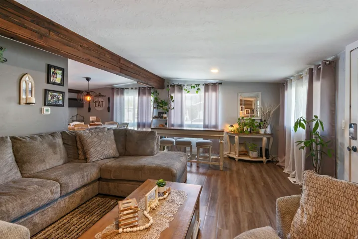 Living room featuring beamed ceiling, dark wood-type flooring, plenty of natural light, and a textured ceiling