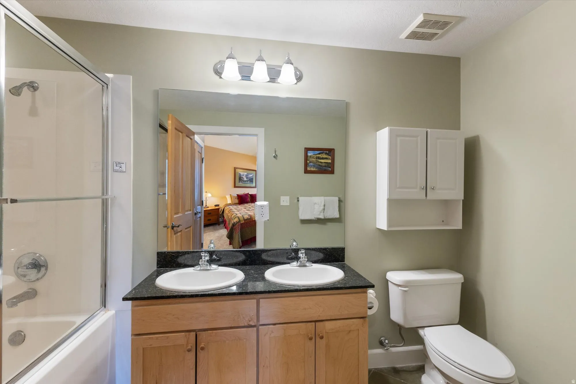 Ensuite bathroom featuring double vanity and shower / bath combination with glass door