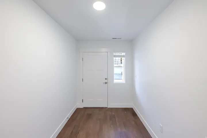 Wood-finish flooring, white walls, and a contemporary flush-mount ceiling light