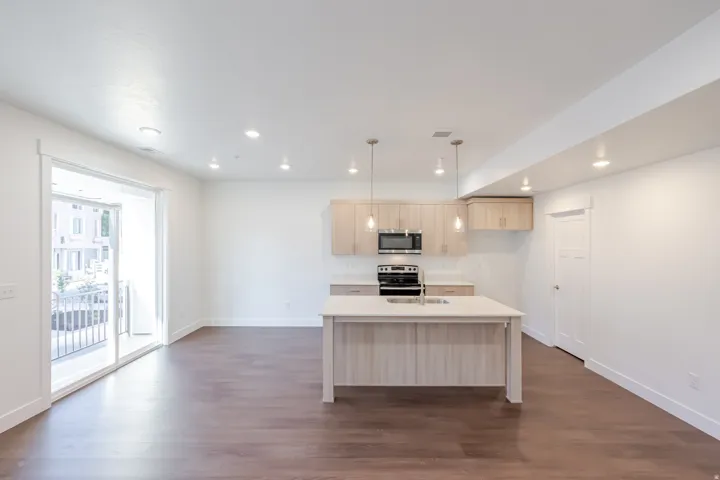Kitchen island with integrated sink, stainless steel appliances, wood-finish cabinetry, and recessed lighting