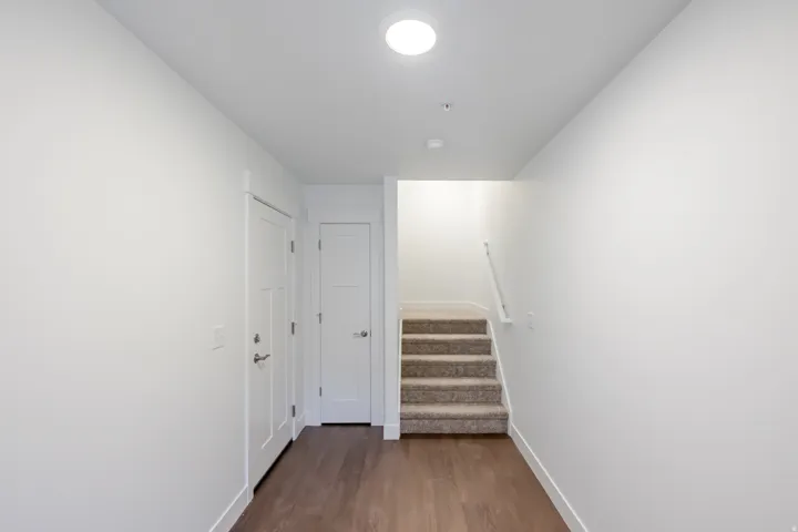 Hardwood-style flooring with white baseboards, a carpeted staircase, and recessed lighting