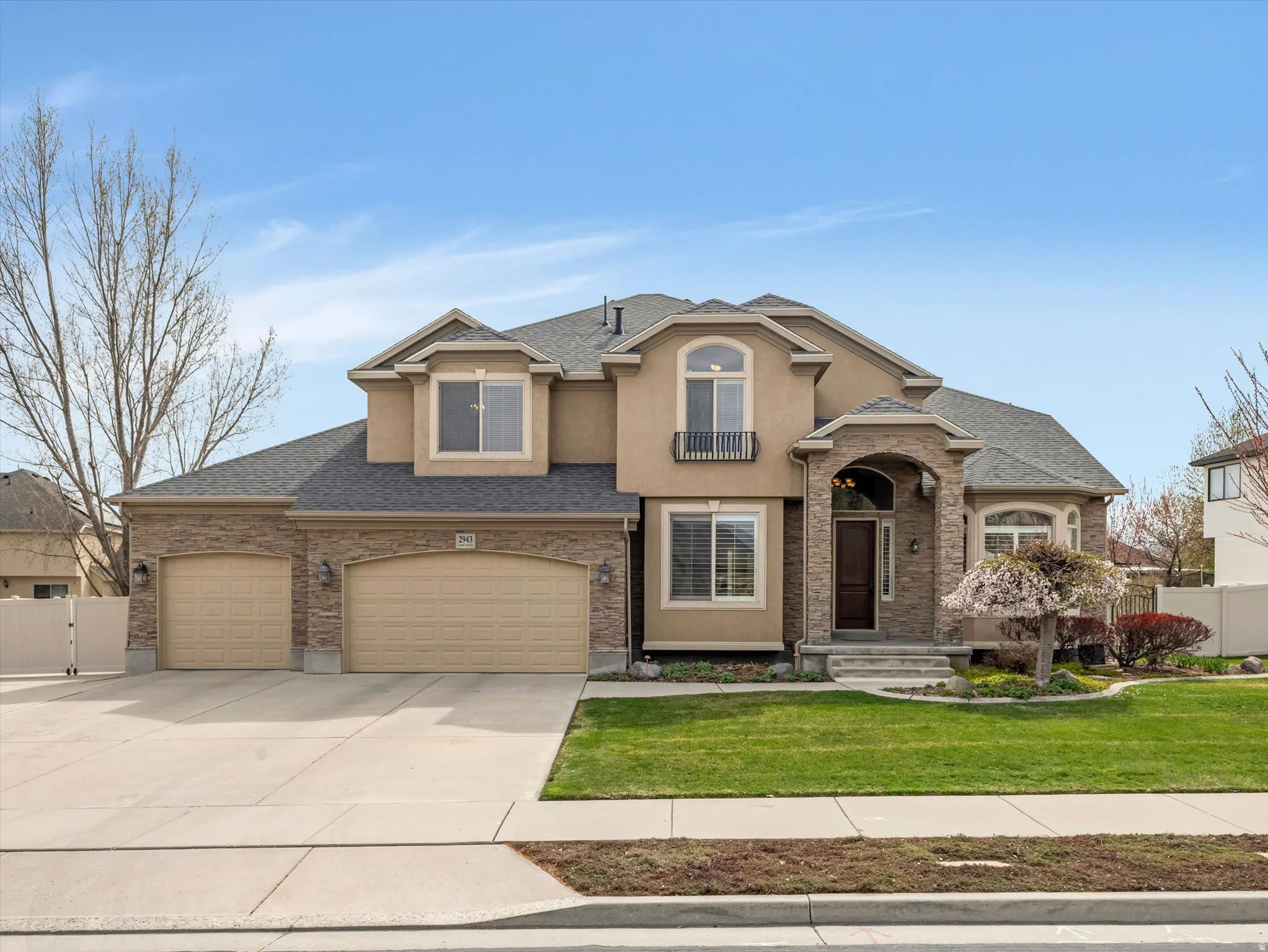 View of front of property with a gate, concrete driveway, an attached garage, a shingled roof, and stucco siding