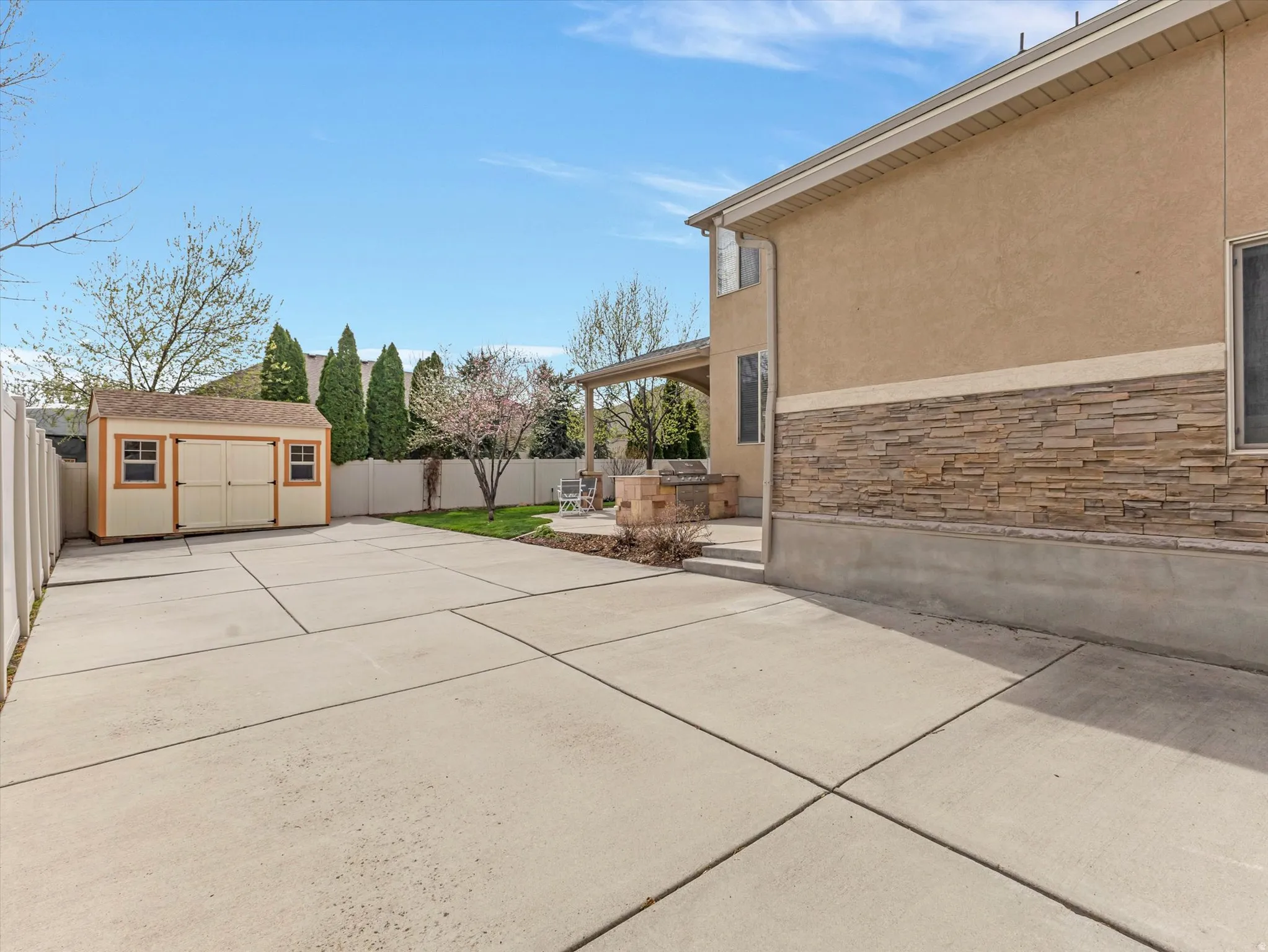 Fenced backyard with a patio area, a storage shed, and concrete driveway