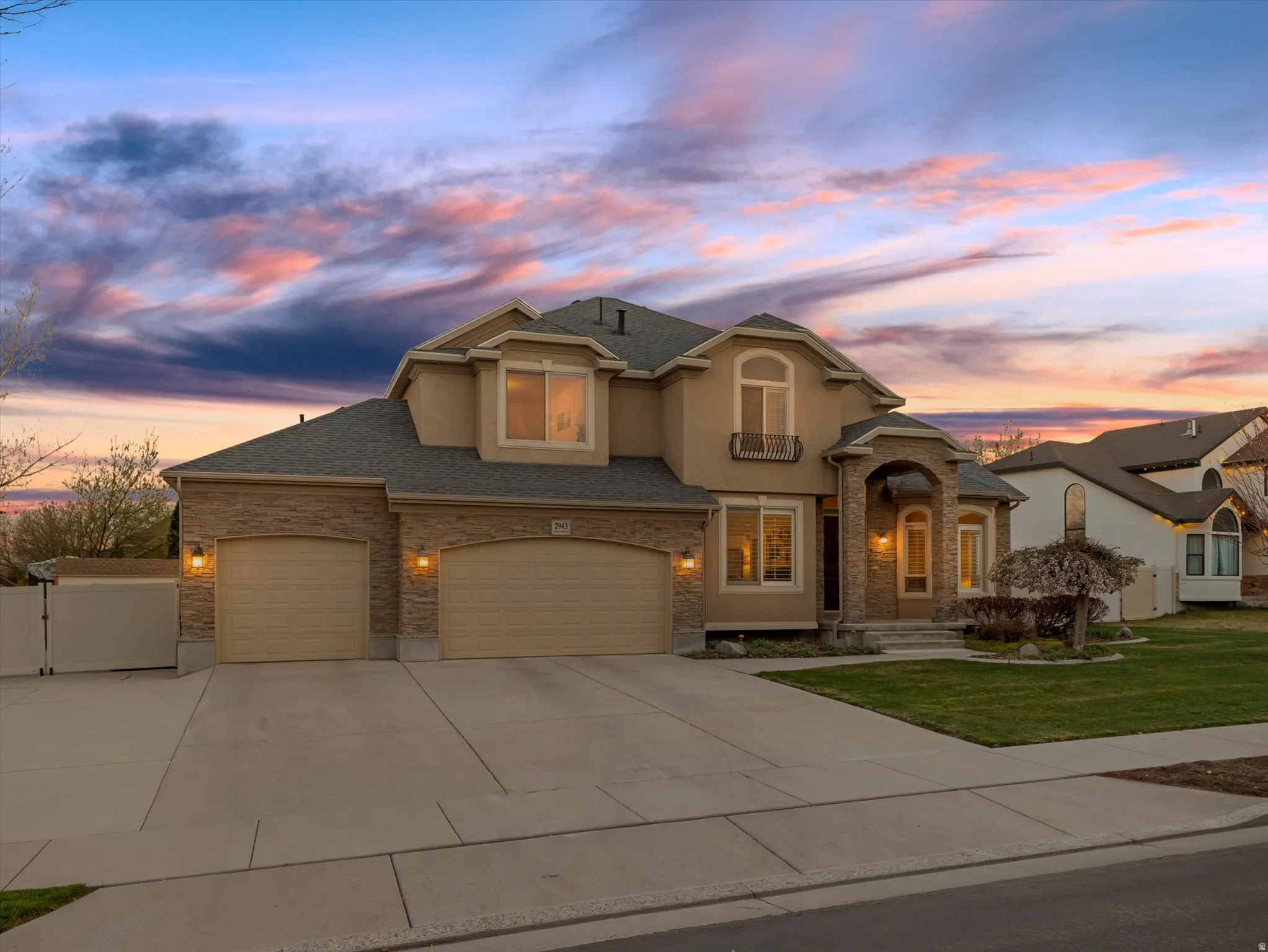 View of front facade with driveway, an attached garage, stucco siding, a front lawn, and roof with shingles
