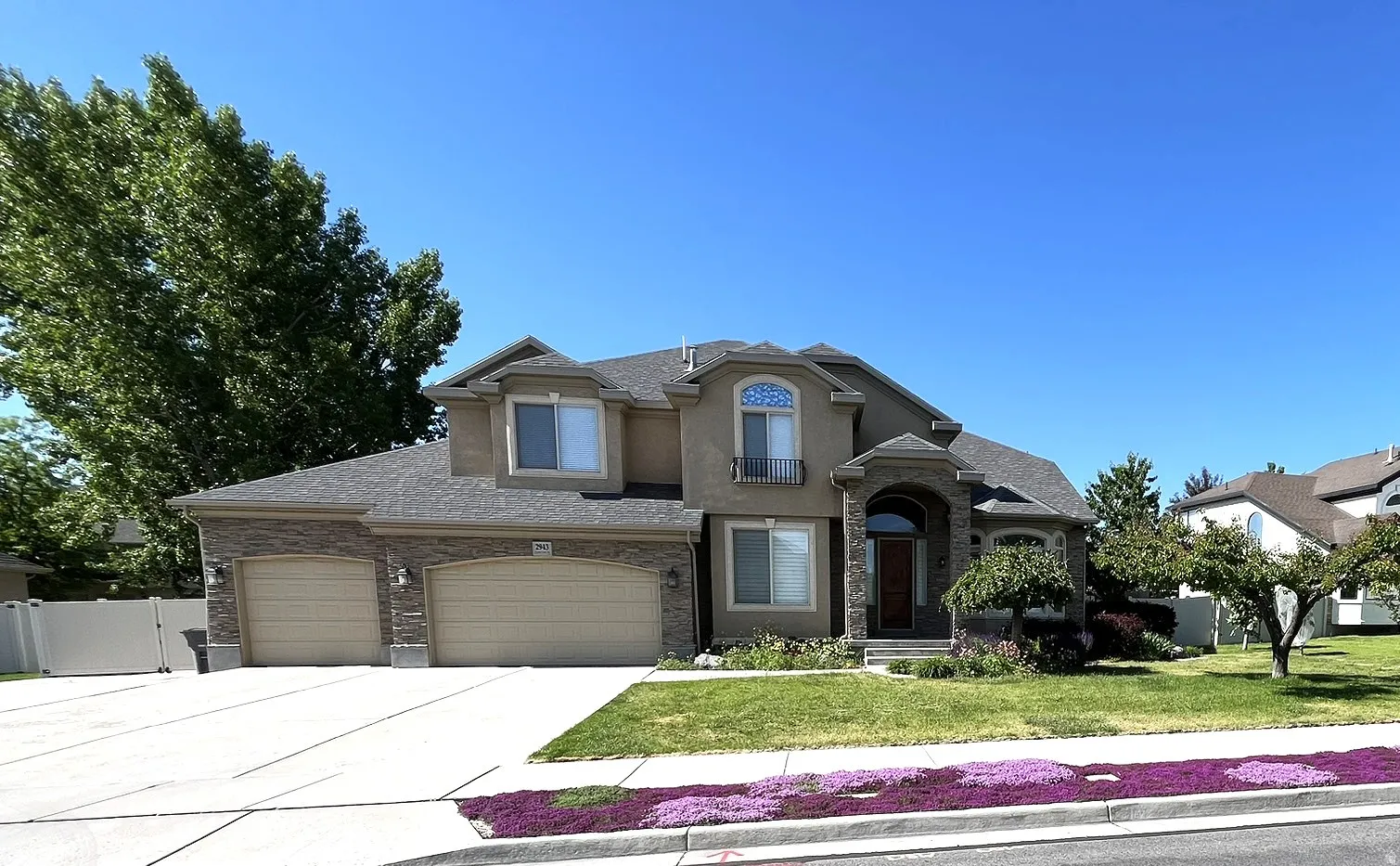 Traditional-style house with a gate, concrete driveway, stucco siding, an attached garage, and roof with shingles