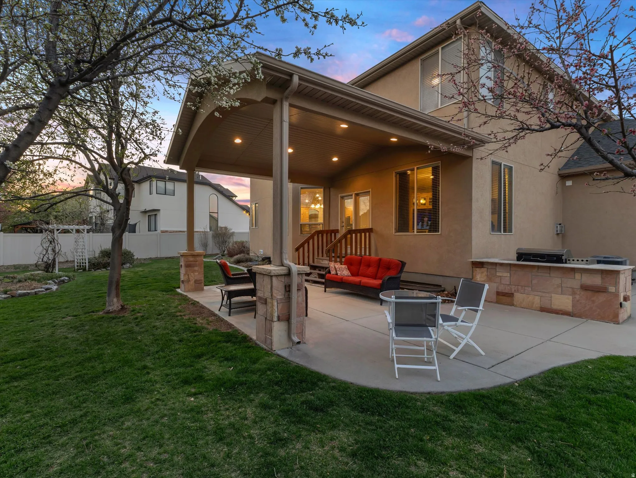 Back of property featuring a patio area, stucco siding, an outdoor kitchen and area to lounge, and a fire pit