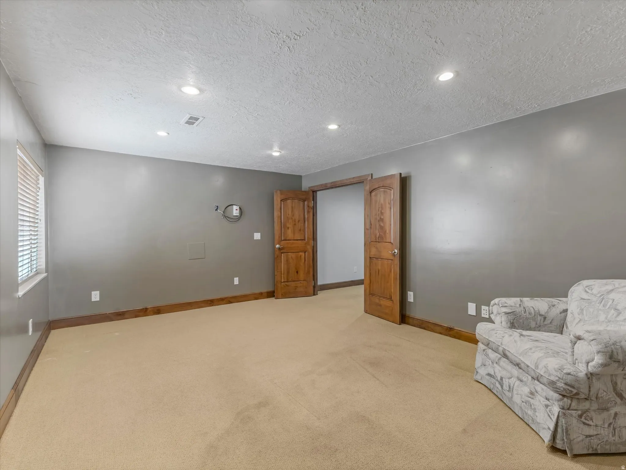 Unfurnished room with light colored carpet, a textured ceiling, and recessed lighting