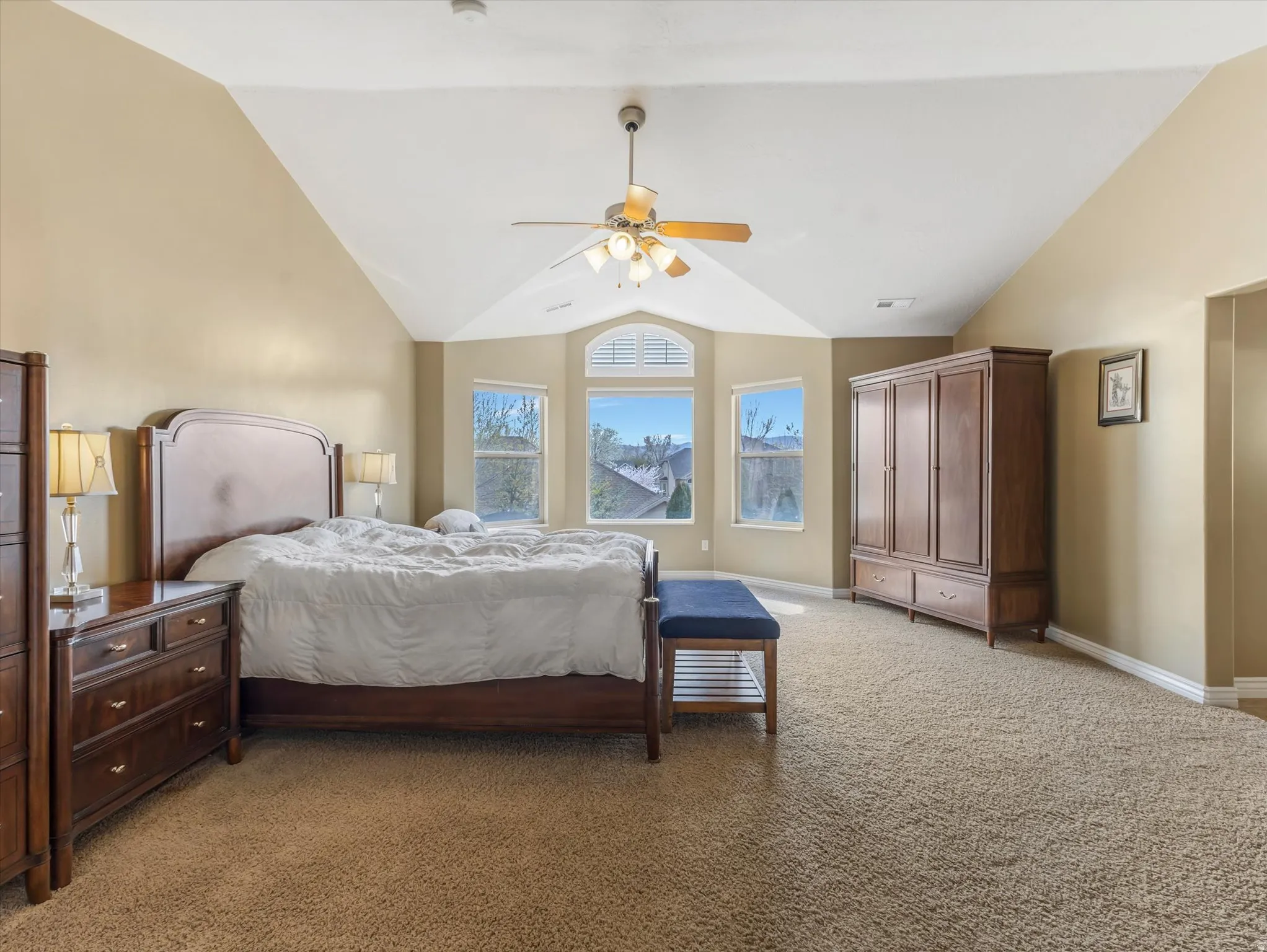 Bedroom featuring light carpet, lofted ceiling, and ceiling fan