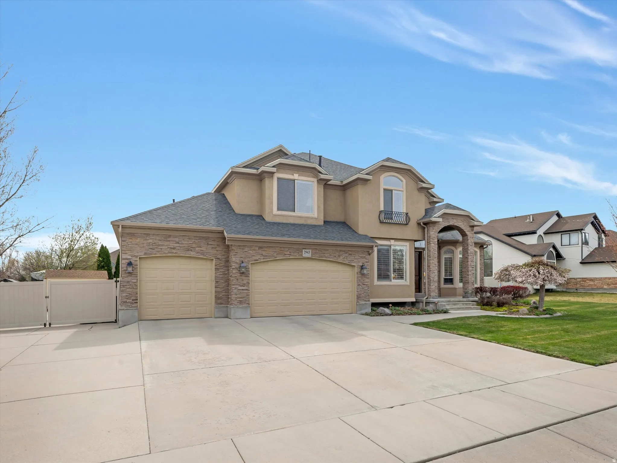 Traditional home featuring a gate, concrete driveway, a garage, stucco siding, and roof with shingles
