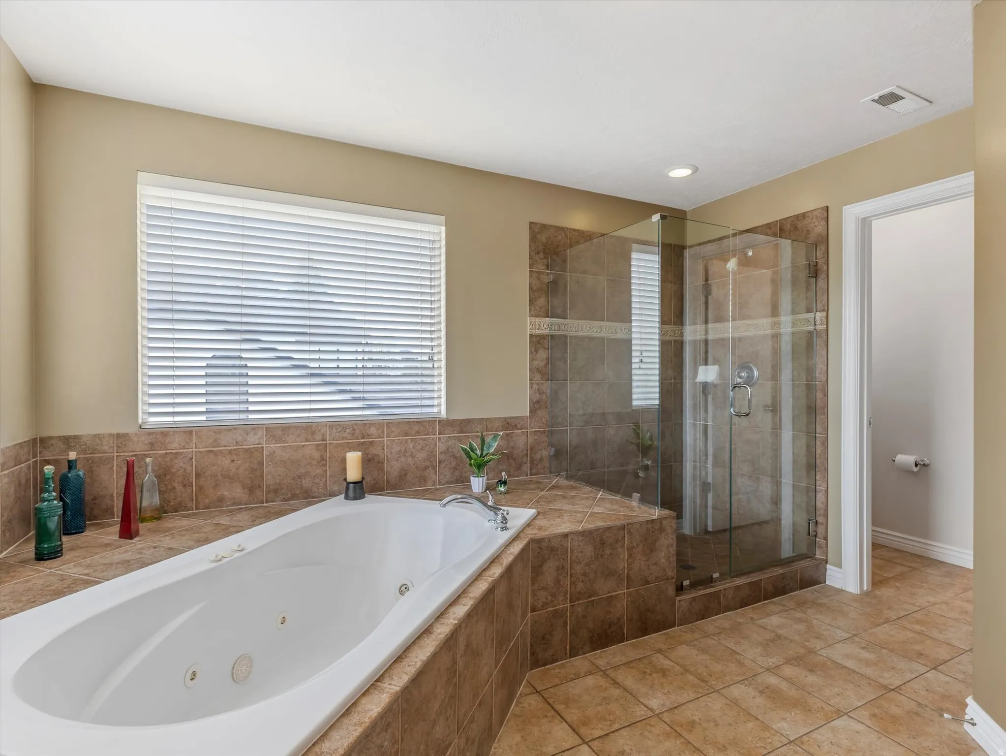Bathroom with a stall shower, a tub with jets, and healthy amount of natural light