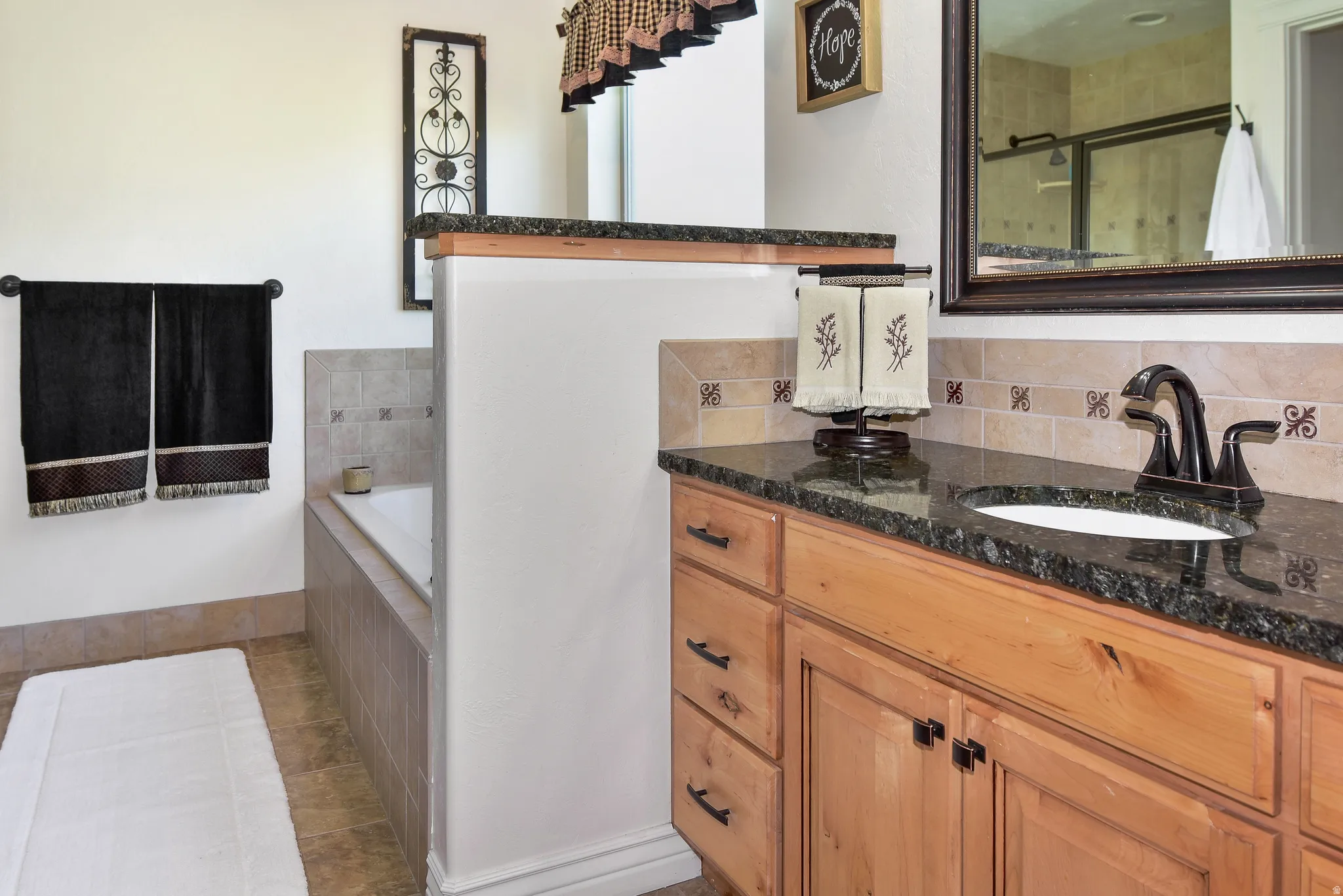 Bathroom featuring vanity, a bath, light tile patterned flooring, and tiled shower