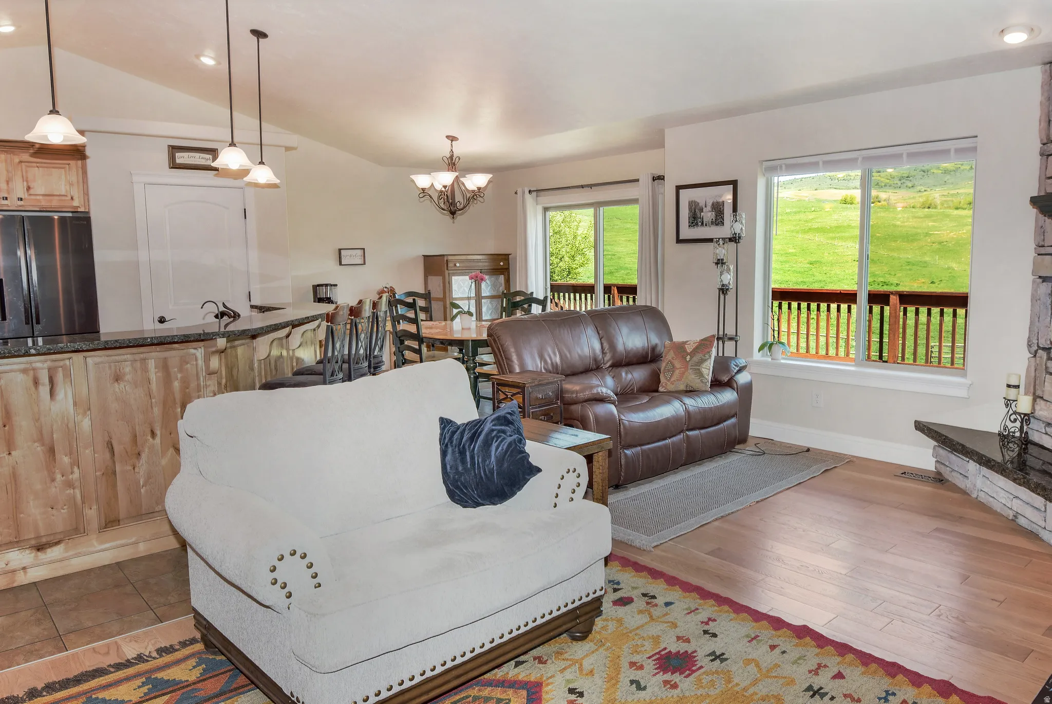 Living room with vaulted ceiling, hanging lights, and light wood-style flooring