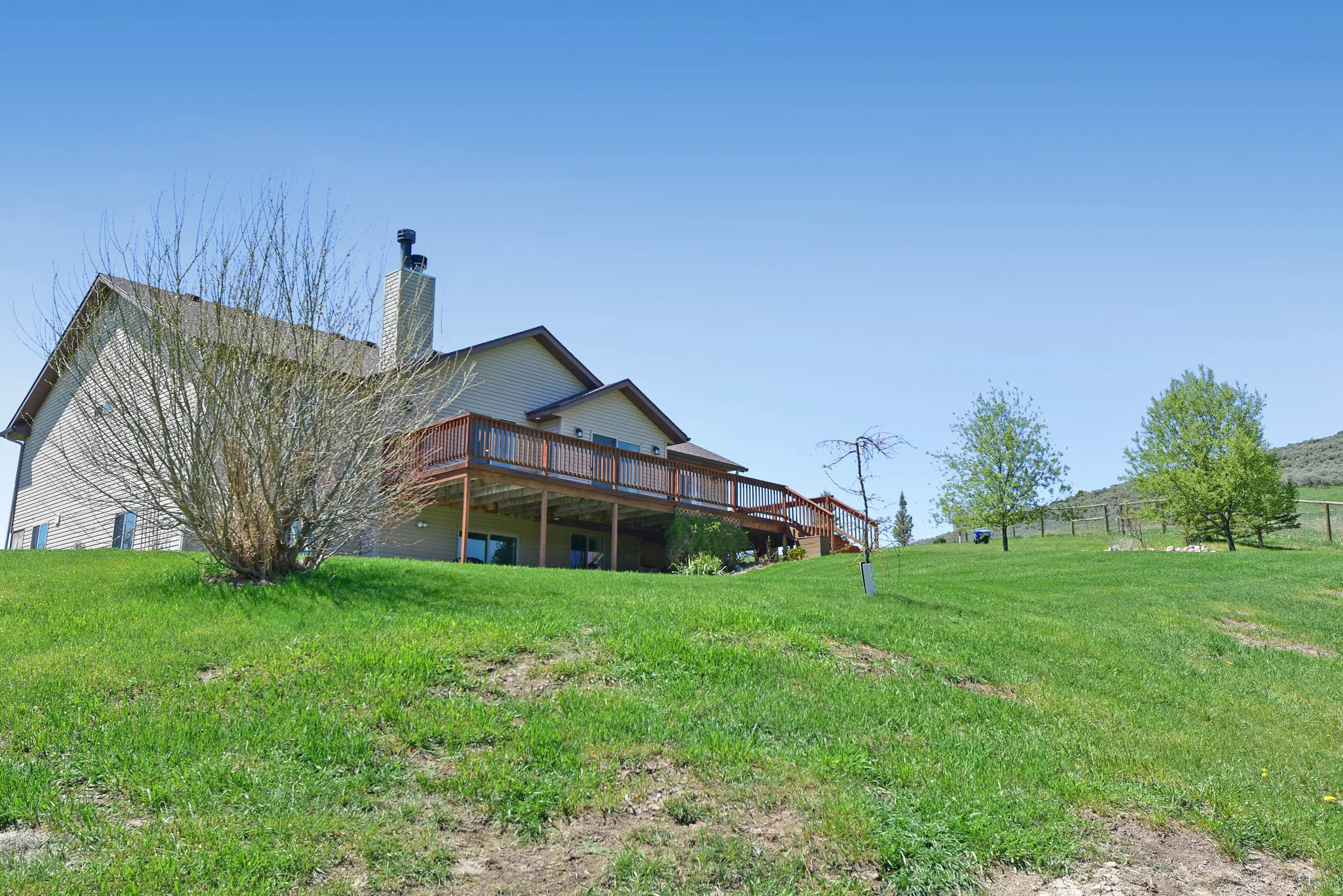 Back of house featuring a deck, a chimney, and a yard