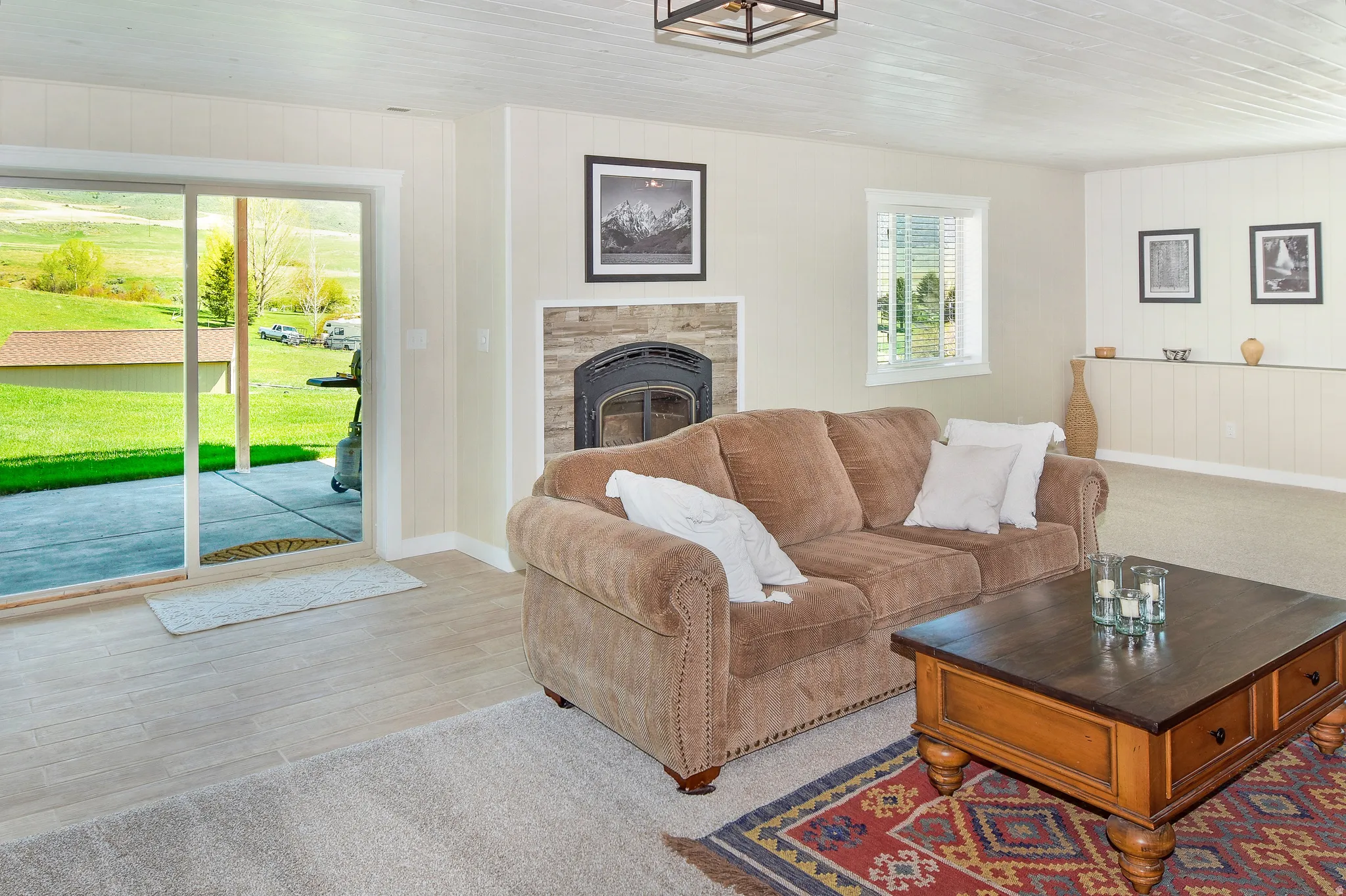 Living room featuring a glass covered fireplace, wooden walls, and light wood-style flooring