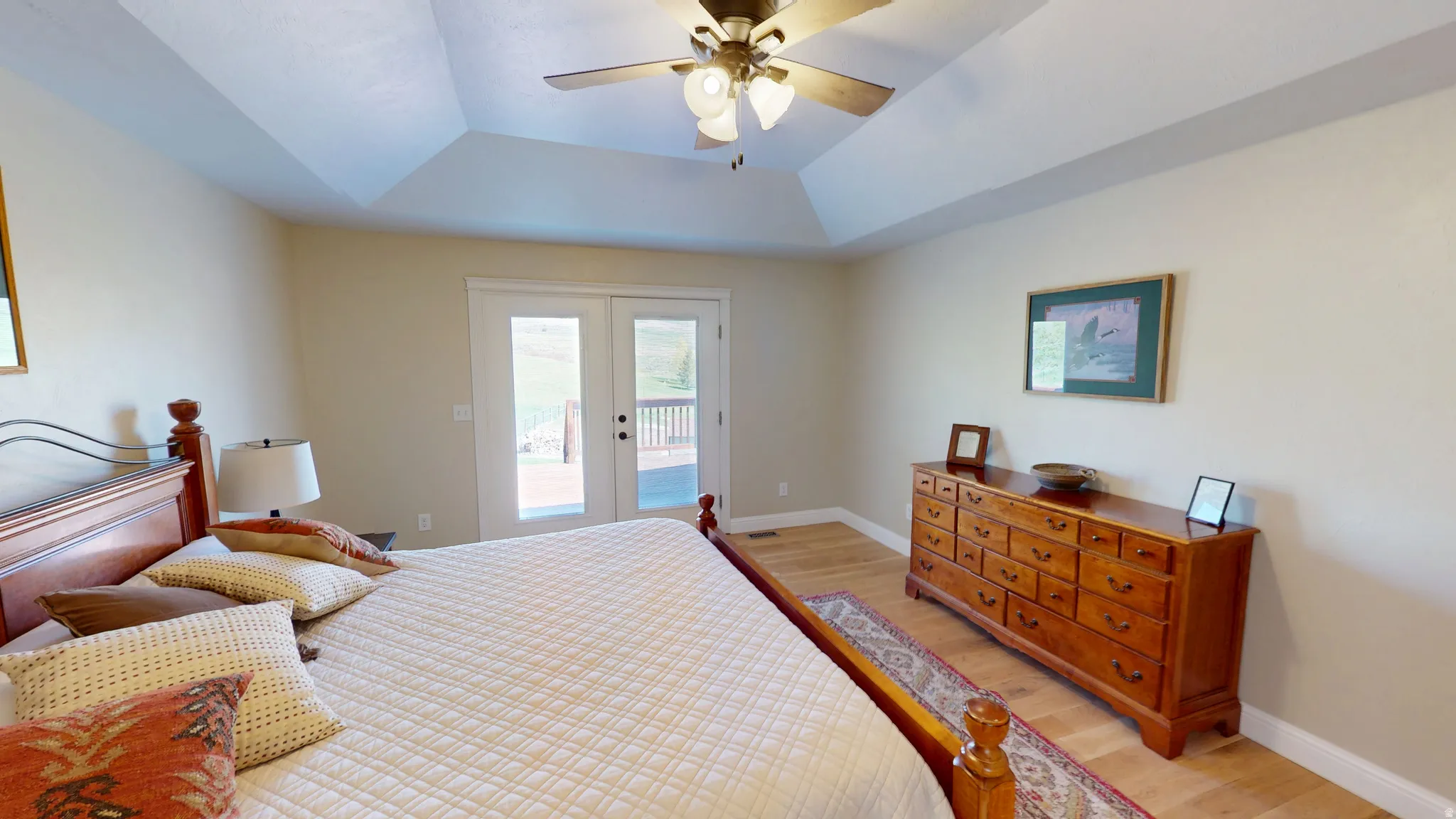 Bedroom featuring light wood-style floors, access to exterior, a raised ceiling, ceiling fan, and french doors