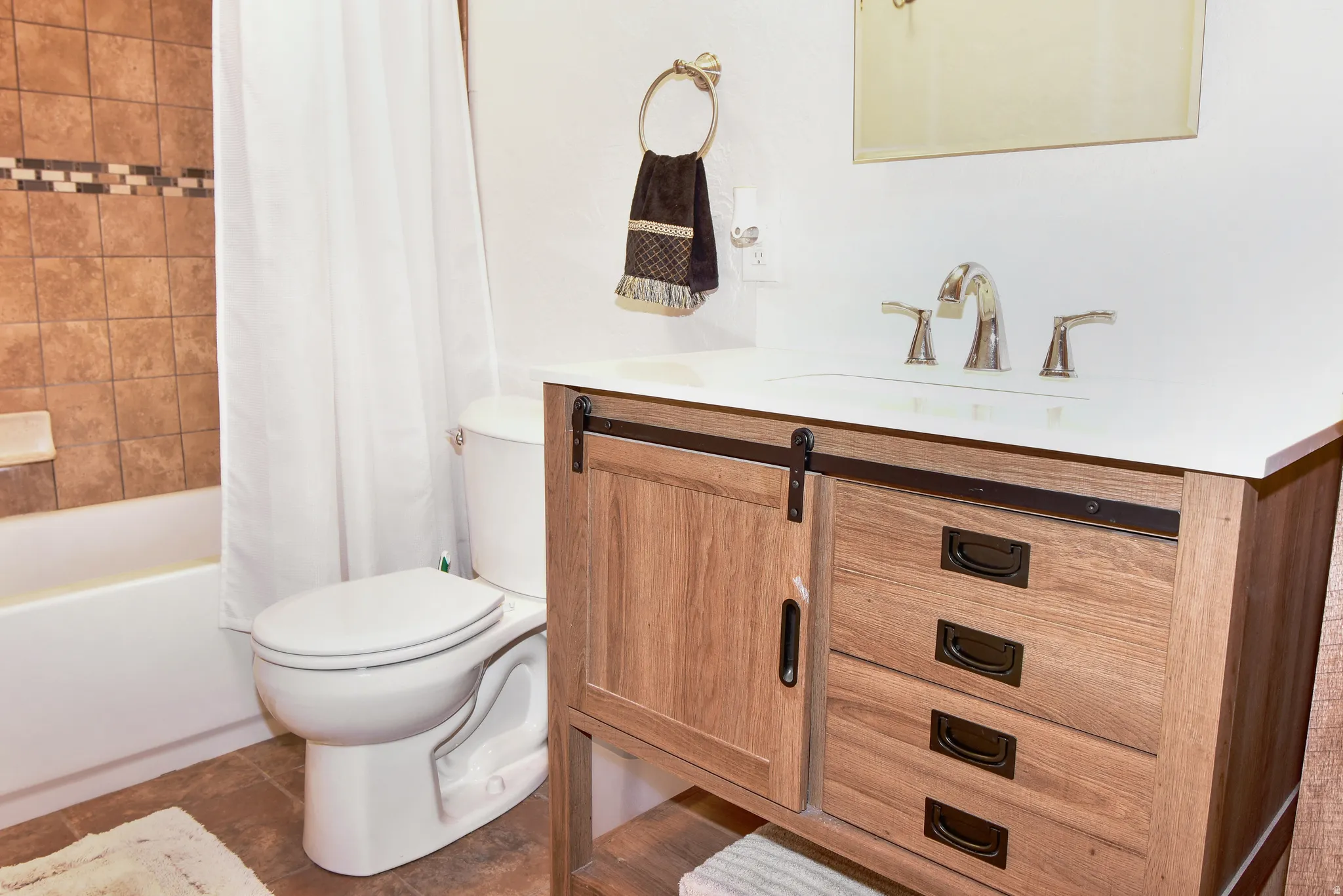 Full bath featuring vanity, shower / tub combo with curtain, and dark tile patterned floors
