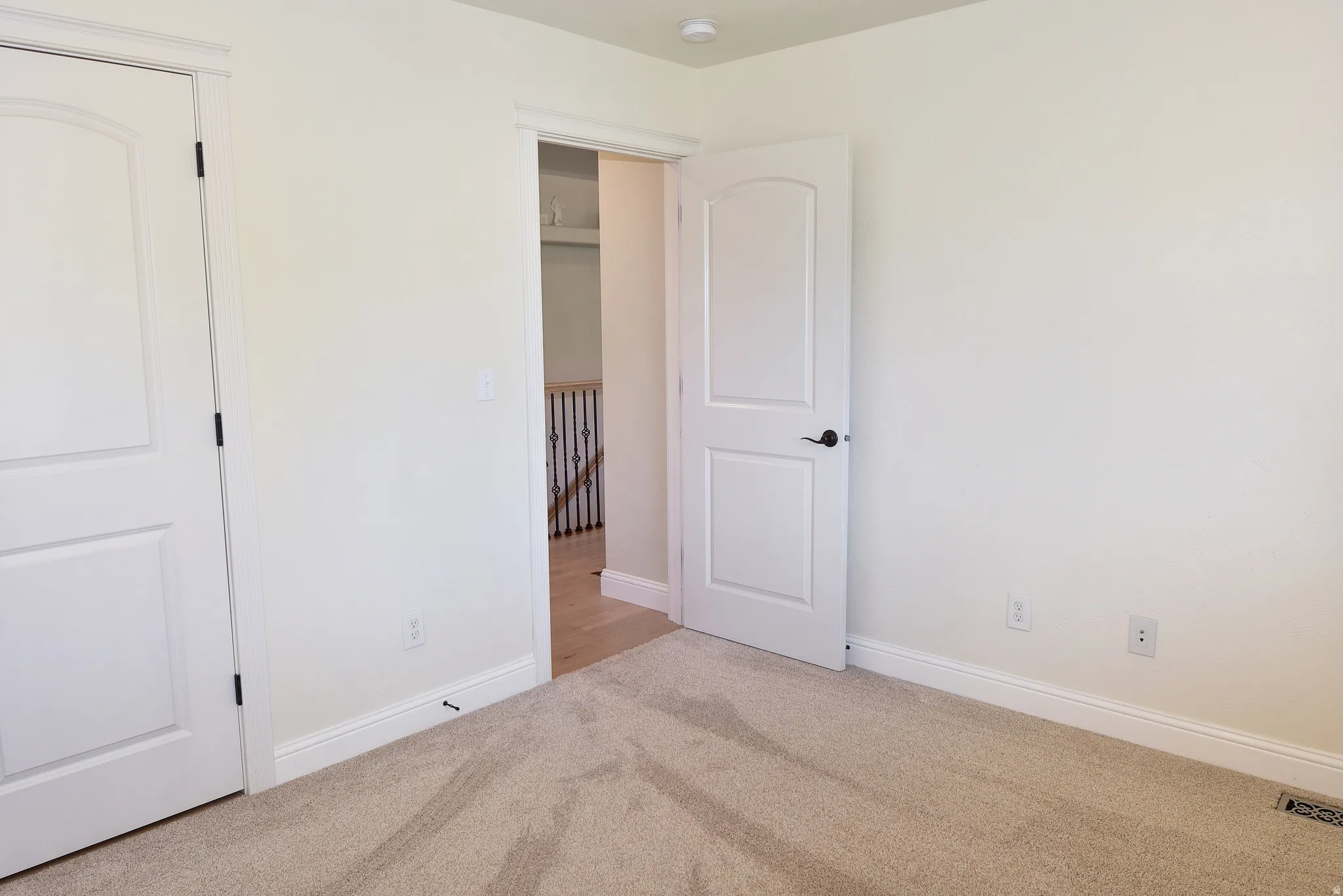 Unfurnished bedroom with light carpet and baseboards