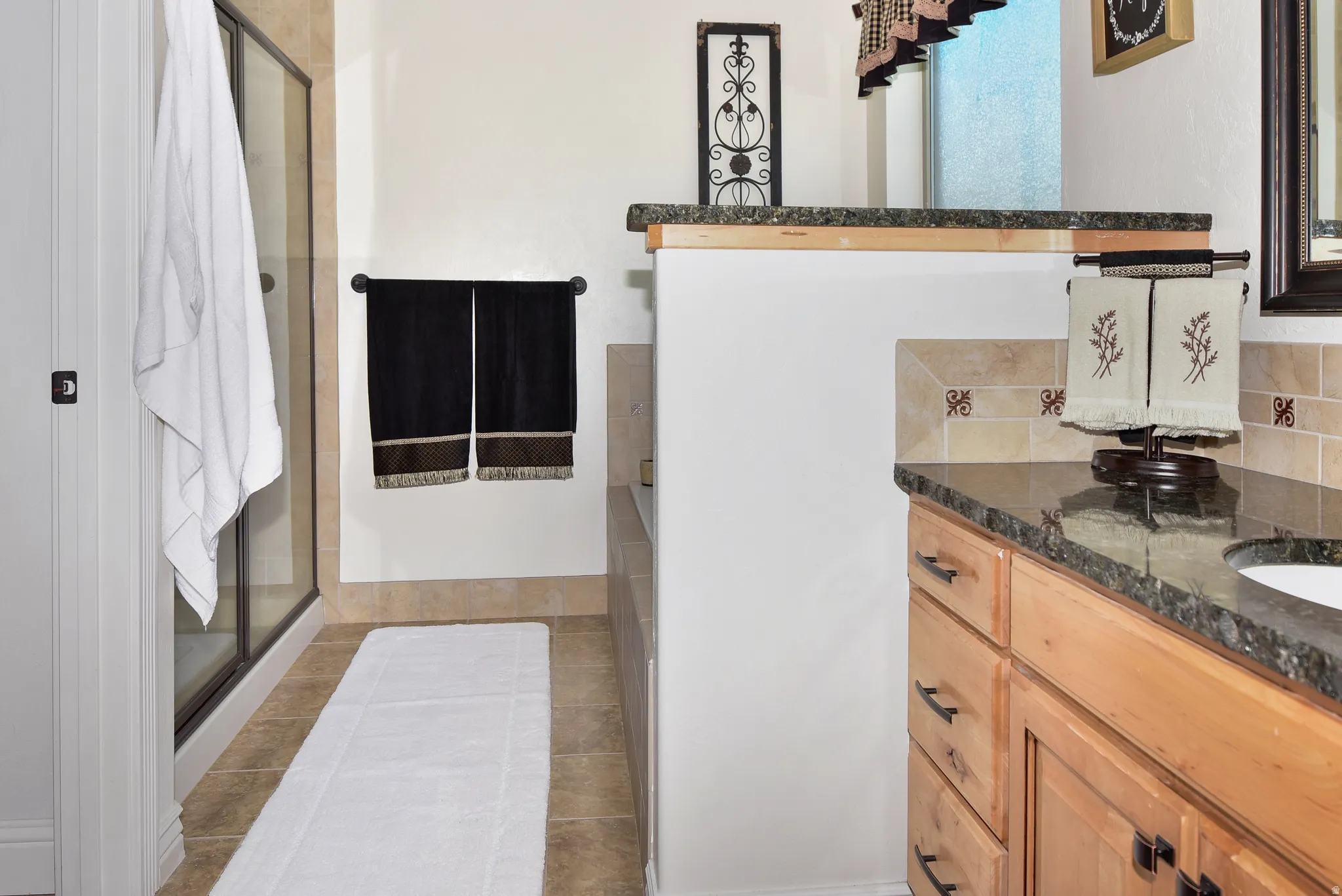 Full bath featuring vanity, a shower stall, decorative backsplash, and light tile patterned flooring