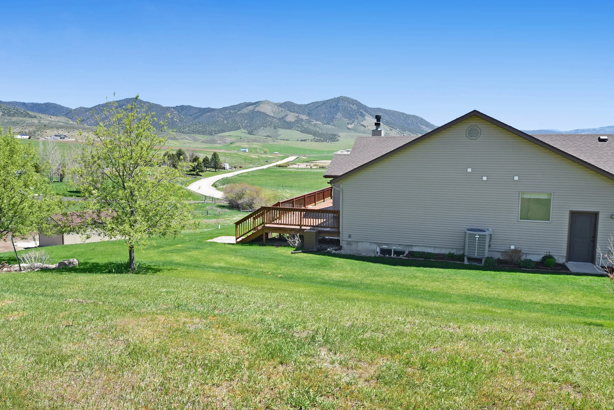 View of side of property with a deck with mountain view, a yard, and a chimney