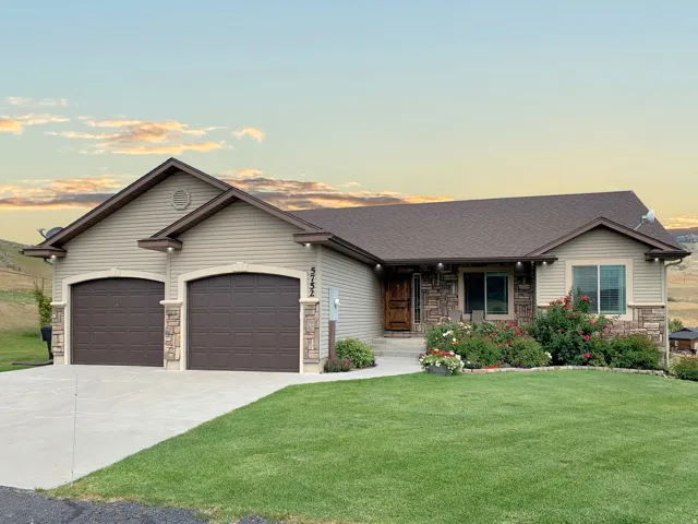 Single story home with stone siding, a porch, driveway, a front yard, and a shingled roof