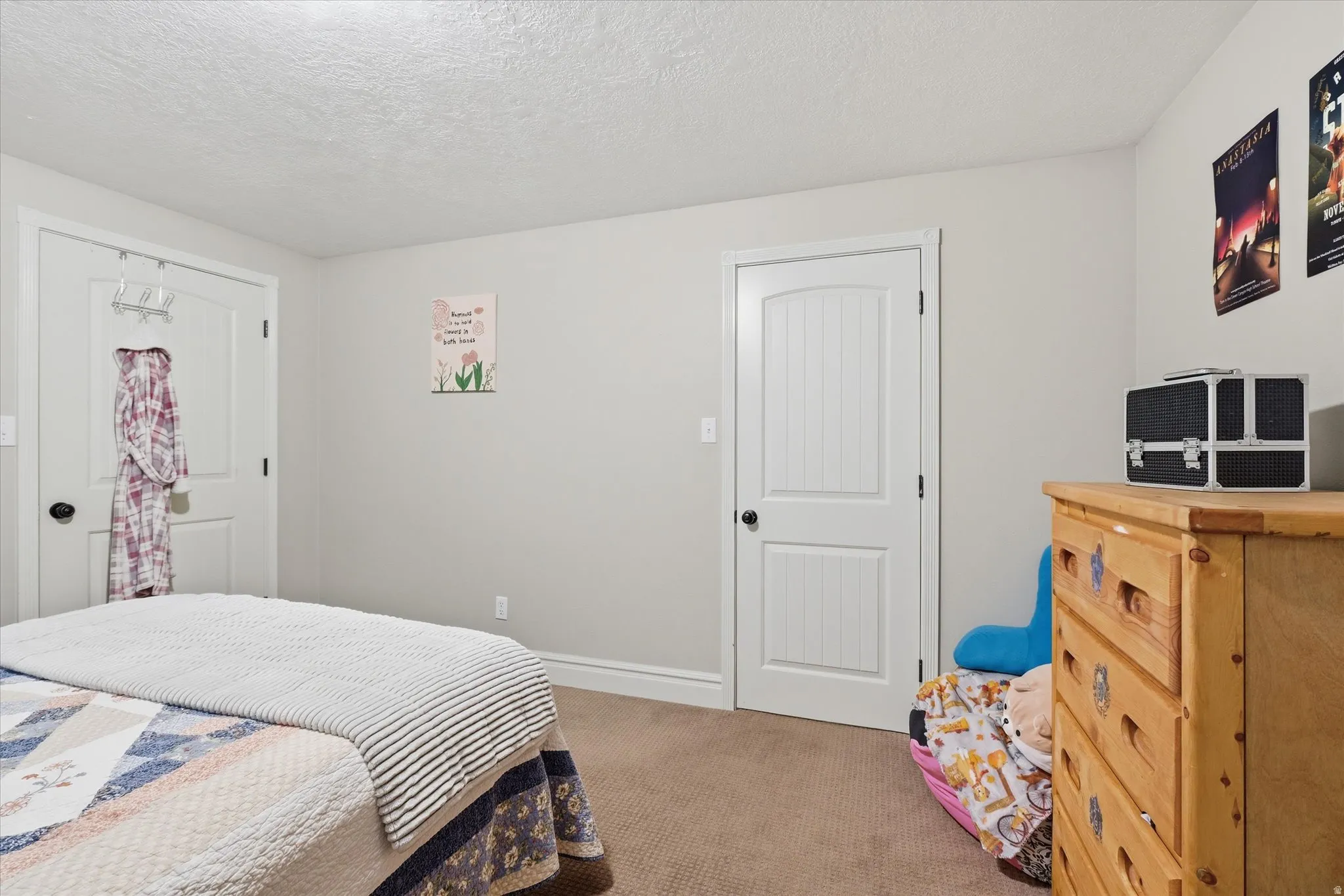 Bedroom featuring light colored carpet and a textured ceiling