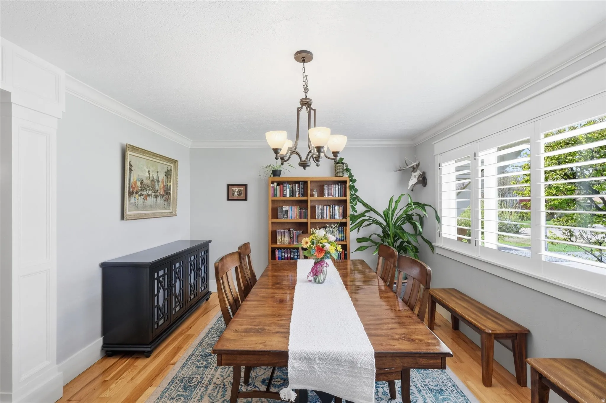 Dining space with light wood-style floors, ornamental molding, and suspended lighting