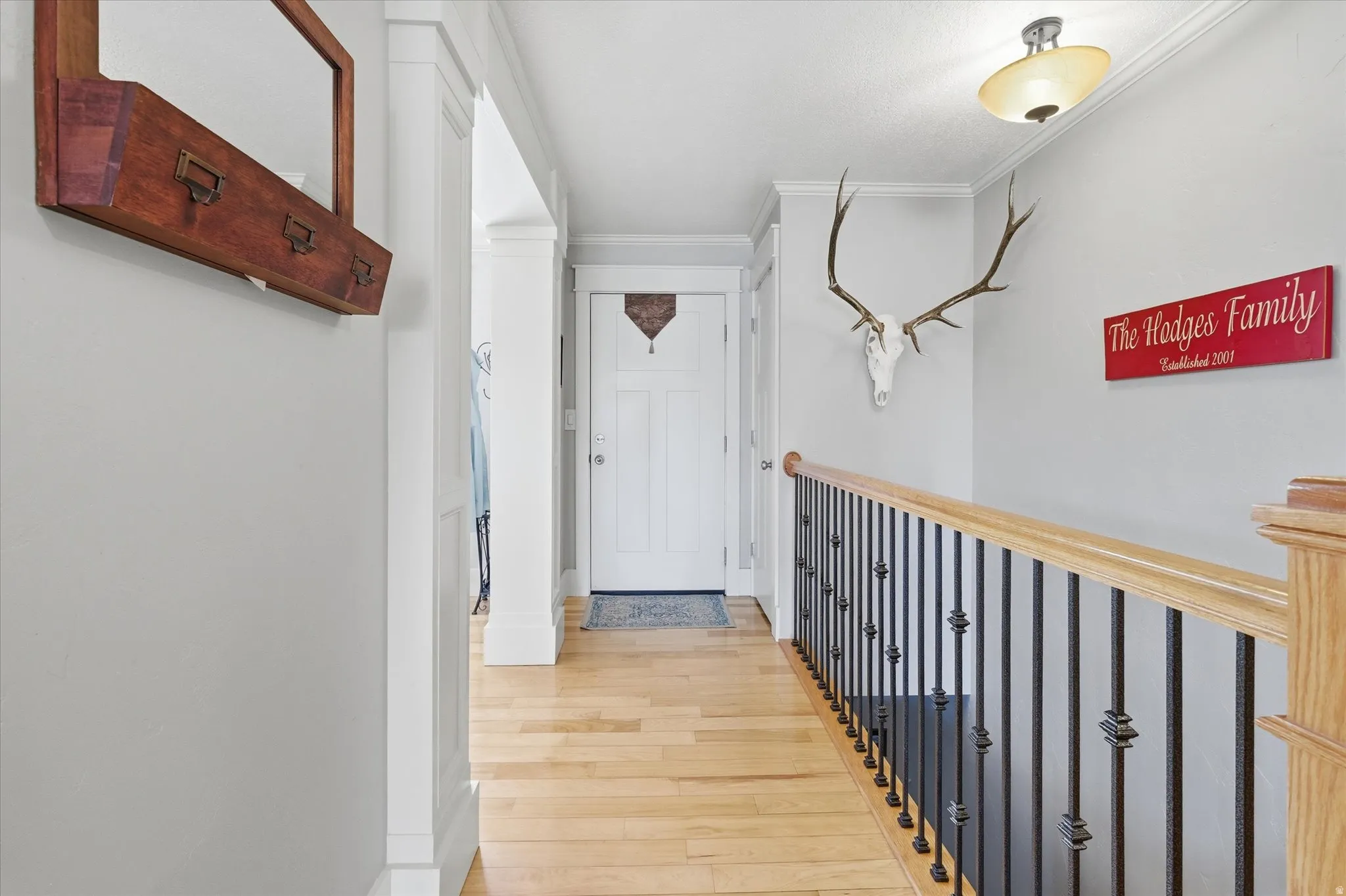 Hall with light wood-style flooring and crown molding