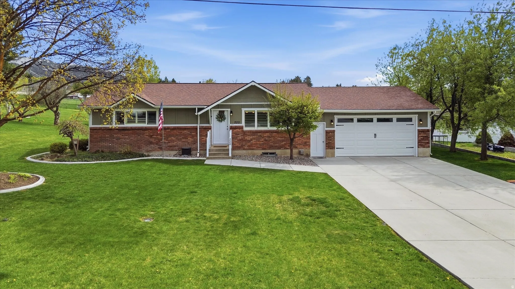 Ranch-style home featuring a front yard, an attached garage, concrete driveway, brick siding, and entry steps