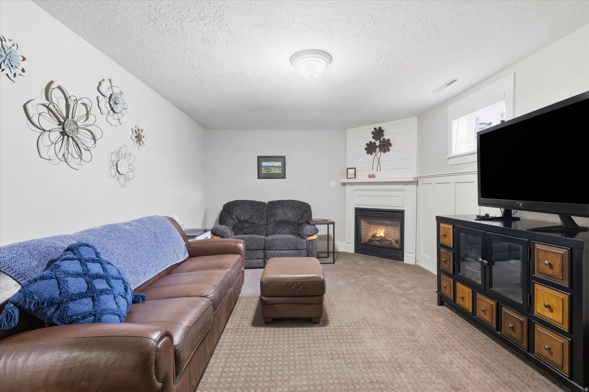 Carpeted living area featuring a glass covered fireplace and a textured ceiling