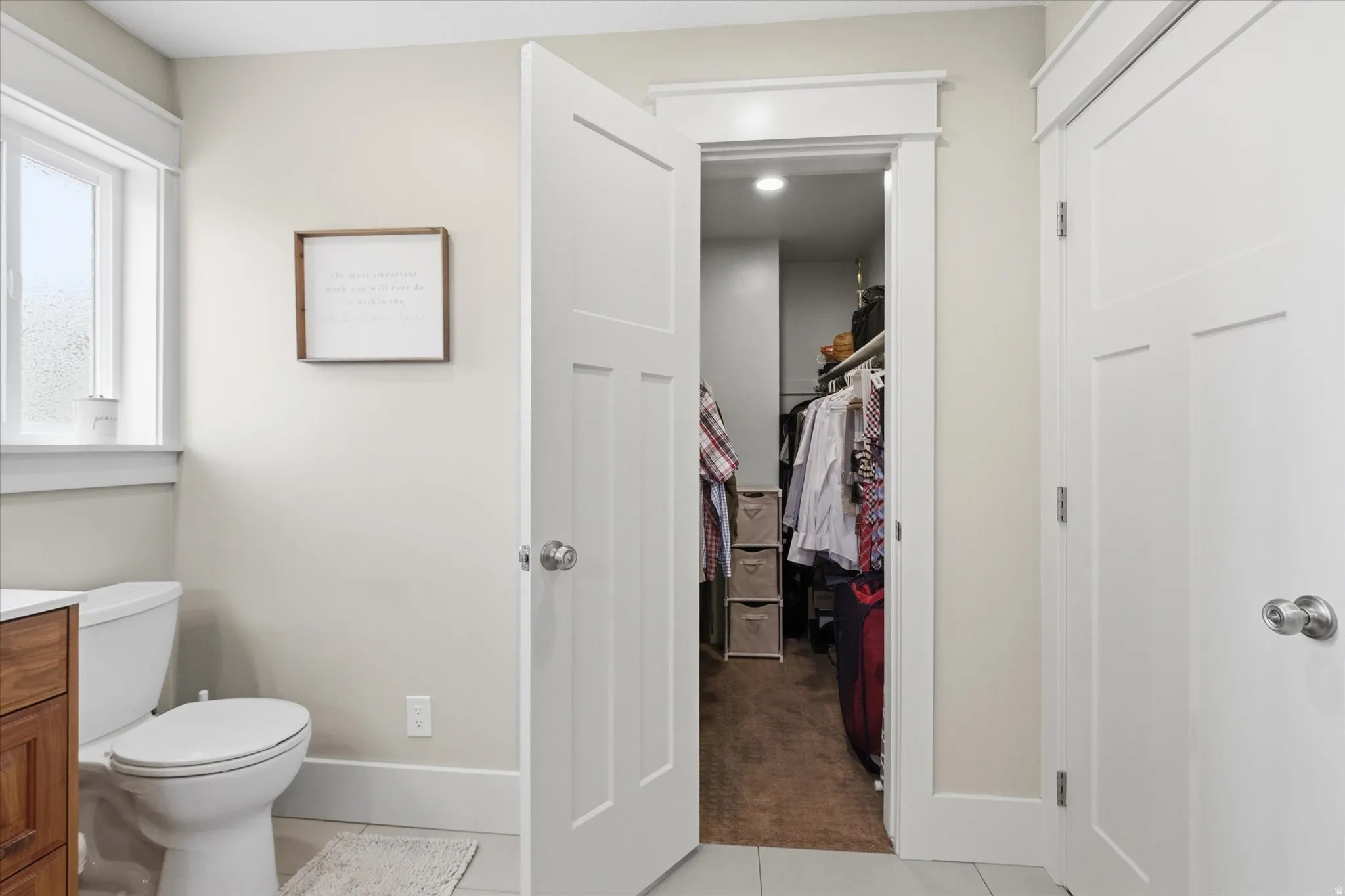 Bathroom featuring vanity, light colored carpet, light tile patterned flooring, and a walk in closet