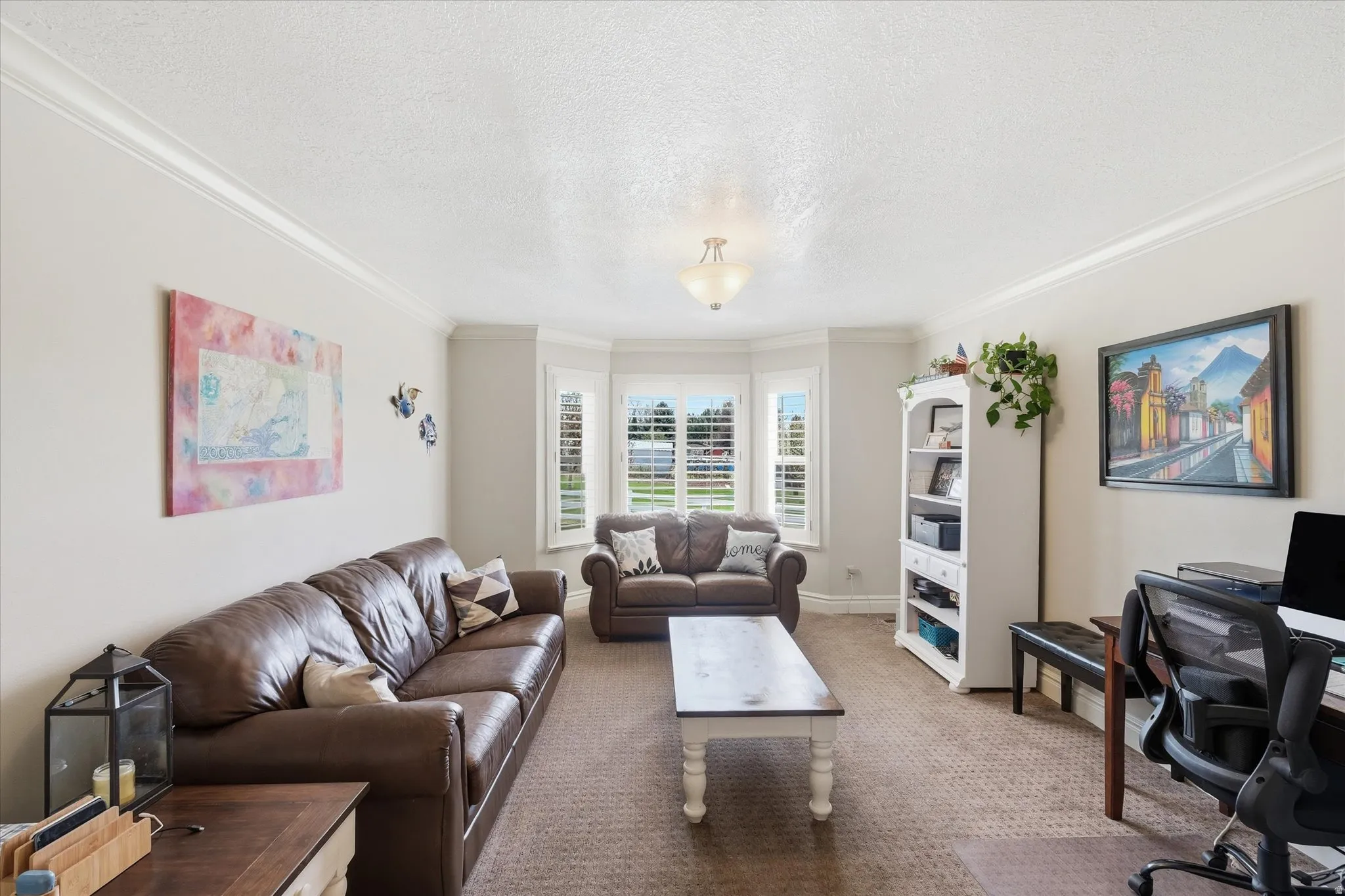 Living area with a desk, light carpet, a textured ceiling, and ornamental molding