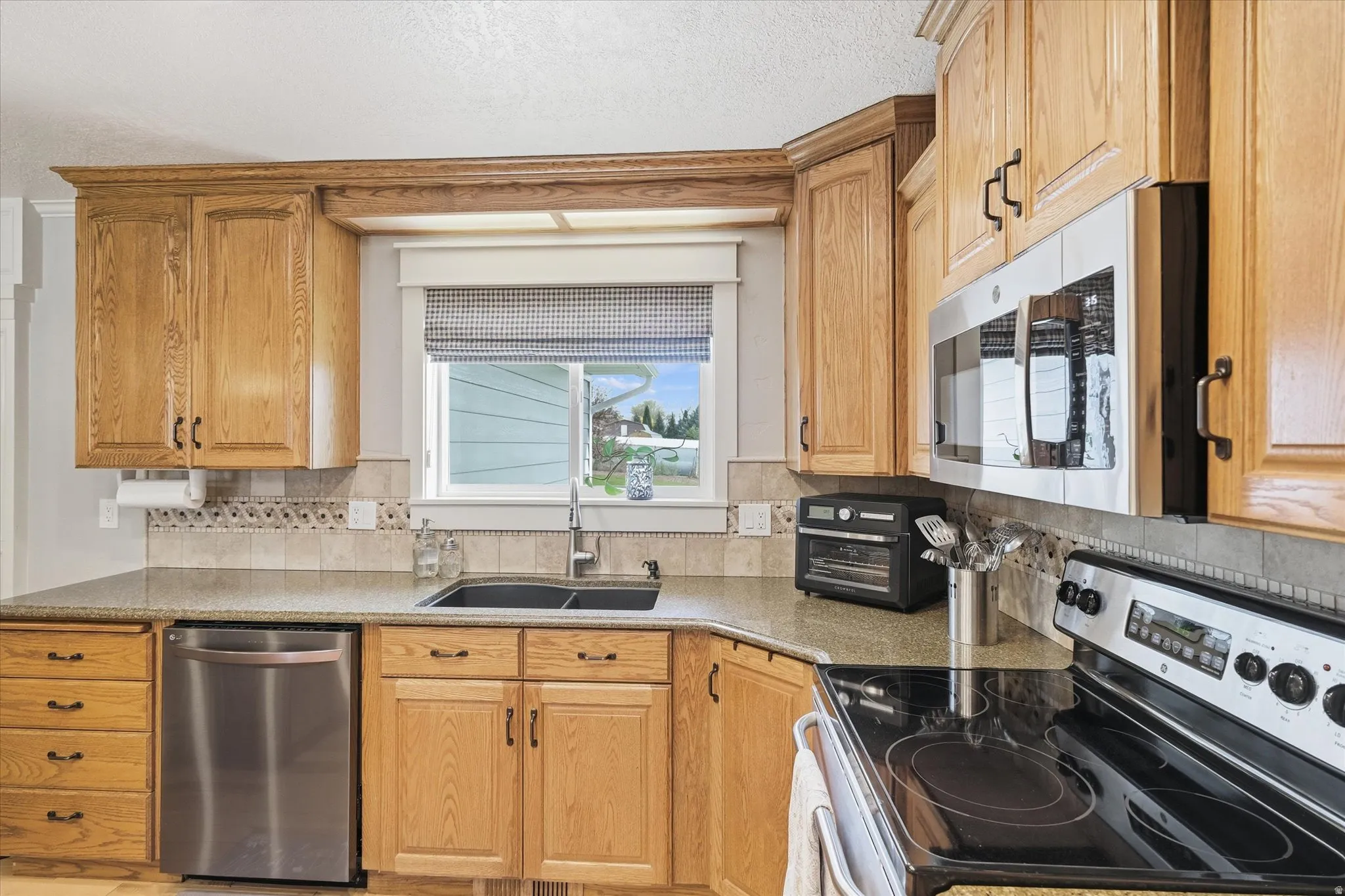 Kitchen featuring stainless steel appliances, light stone countertops, and tasteful backsplash