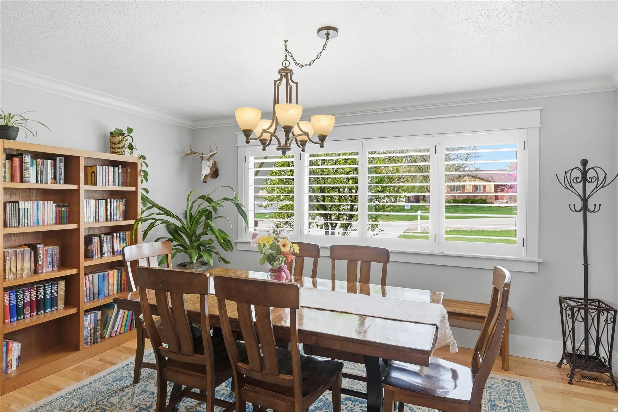 Dining area with light wood-style flooring, suspended lighting, crown molding, and a textured ceiling