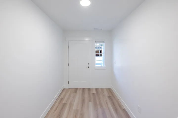 Entryway featuring wood-finish flooring, a white paneled door, and a transom window