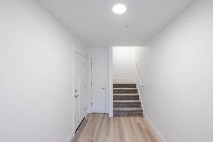 Wood-finish flooring, recessed lighting, and a carpeted staircase with a white handrail