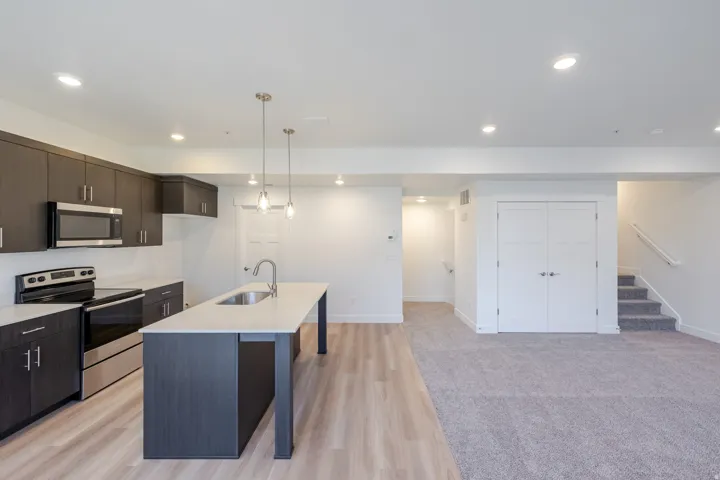 Kitchen with dark wood-finish cabinetry, stainless steel appliances, and a central island with a sink