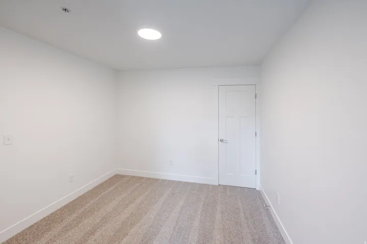Neutral-toned carpet flooring, recessed ceiling lighting, and a paneled interior door
