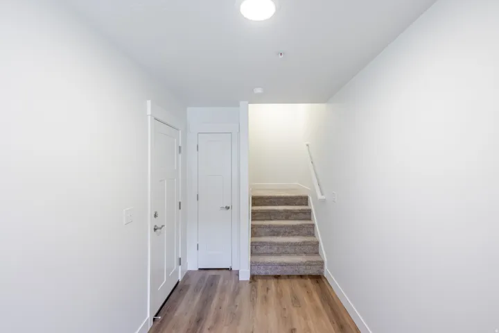 Wood-finish flooring, white doors, and a carpeted staircase