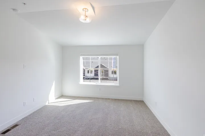Recessed window with blinds, light-toned carpet flooring, neutral wall color, and a ceiling-mounted light fixture